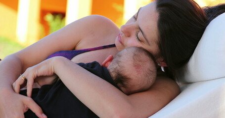 Wall Mural - Candid mother holding with baby infant outside by the pool laying down showing care