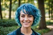 © ThomasLENNE - portrait of smiling woman with blue hair against trees in park