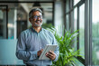 © wolfhound911 - Middle-aged Indian CEO executive businessman looking aside while holding a digital tablet. A mature smiling professional entrepreneur investor contemplating finance trading strategy while standing in