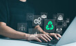 Sustainable development planning concept. Person using a laptop with virtual icons related to recycling, renewable energy, and environmental protection. ESG business sustainability investment strategy