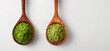 Two wooden spoons with ground green tea powder, green matcha powder, antioxidant on a white background, top view
