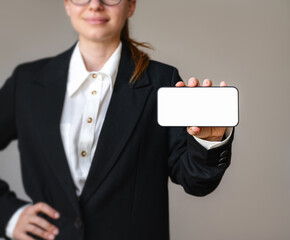 Mobile phone with white blank screen in hand of young businesswoman. Woman showing screen of her smartphone.