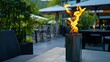 pyramid tower gas flame torch, illuminating an open garden space adorned with sofas and tables, showcasing the close-up detail of the warm flames against a blurred background of lush greenery.