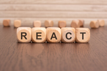 Sticker - the text 'REACT' is written on wooden cubes on a brown background