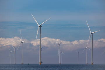 Wind farm of wind mills, generators, wind turbines, off shore in a sea or lake IJsselmeer in the Netherlands. Multiple tall windmills and rotor blades generating green sustainable energy, electricity