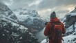 © Matthew - Equipped with a camera, a traveler stands before a mesmerizing mountain landscape blanketed in snow