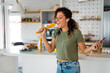 © Dorde - Young woman listening music on the headphones and singing while making pasta for lunch.