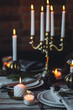 Beautiful table setting for family Christmas dinner at home. Cozy atmosphere, candlelight. Wine glasses, vintage chandelier, elegant interior. Fir tree branches, wooden furniture, dark, bokeh