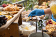 Gloved hand of caterer drizzles honey over dessert cake as finishing touches are made before guest arrive.