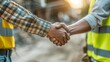 ©  Green Creator - Architect and engineer construction workers shaking hands while working at outdoors construction site Building construction collaboration concept