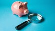Piggy bank and magnifying glass on blue background, savings and economy concept