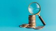 © Kaleb - Stack of coins and magnifying glass on blue background, investment analysis concept
