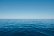 A vast expanse of deep blue sea, with the horizon line stretching across an endless sky of clear and unbroken light blue color, ripples