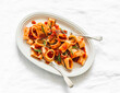 Paccheri pasta with tomato sauce and rosemary is a delicious vegetarian lunch on a light background, top view