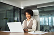 © insta_photos - Professional happy business woman employee working on computer in office. Young busy African American businesswoman female company executive using laptop managing financial project sitting at desk.