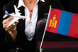 business woman holds toy plane travel bag and flag of Mongolia

