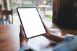 © Farknot Architect - Mockup image of a woman holding digital tablet with blank white desktop screen in cafe