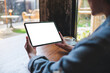© Farknot Architect - Mockup image of a woman holding digital tablet with blank white desktop screen in cafe