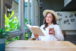 Portrait image of a beautiful young woman with hat drinking iced coffee while reading book