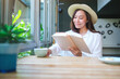 Portrait image of a beautiful young woman with hat drinking coffee while reading book