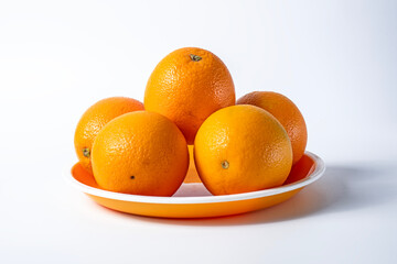 Fresh oranges on a plate isolated on a white background.