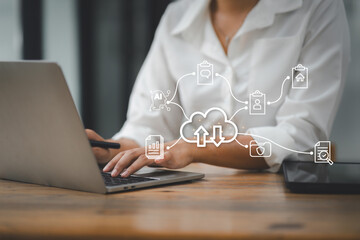 Professional woman working on laptop in office with digital interface showing cloud computing icons. data storage, backup, or online services concept.