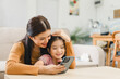 Young mother and daughter enjoying time together with smartphone at home