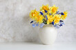 garden daffodils and hyacinths, spring flowers in a potbellied vase on a light background. copy space.