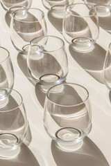 Wall Mural - A collection of minimalist glassware, like stemless wine glasses, arranged in a symmetrical pattern on a clean surface