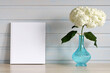 a mockup of a book or album. the empty cover of the booklet. a branch of blooming hydrangea in a blue vase on the table. background, copy space. an empty space for your design.