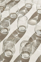 Wall Mural - A collection of minimalist glassware, like stemless wine glasses, arranged in a symmetrical pattern on a clean surface