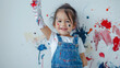 © Aleksandra - A cheerful mixed-race girl wearing overalls is depicted holding an artist's paintbrush, with her hands raised high and splashes of dark red color covering her from painting the wall.