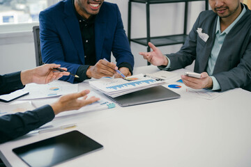 Fototapete - Three men are sitting at a table with papers and cell phones