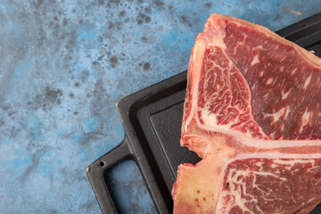 Wall Mural - fresh raw beef steak on blue background, top view