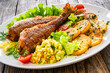 Fried sea bass with fried potatoes and fresh cabbage salad on wooden table

