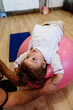 Adorable girl enjoys physical therapy sessions with a qualified therapist in a specialized children's gym or play area.