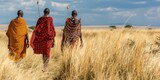 Three men walking in a field wearing traditional African clothing