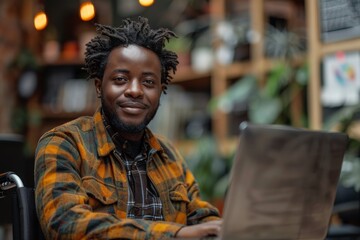 A young man in casual attire works on a laptop amid lush greenery in a bright greenhouse environment