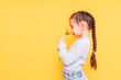 A child smells a yellow flower against a yellow background.