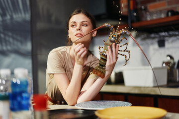 Wall Mural - Woman holding a lobster at a kitchen table, preparing for a delicious seafood meal concept