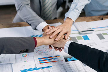 Wall Mural - A group of people are shaking hands on a table with a lot of graphs and charts