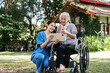 A woman in a blue uniform is helping an elderly woman in a wheelchair