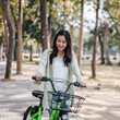 A woman is riding a green bicycle with a basket on the front