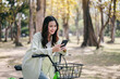 A woman is riding a bicycle and looking at her cell phone