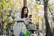 A woman is riding a bike and looking at her phone