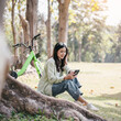 A woman is sitting on the grass with a green bicycle behind her
