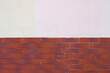 Half of the red brick wall is painted over with white plaster. Abstract construction background.