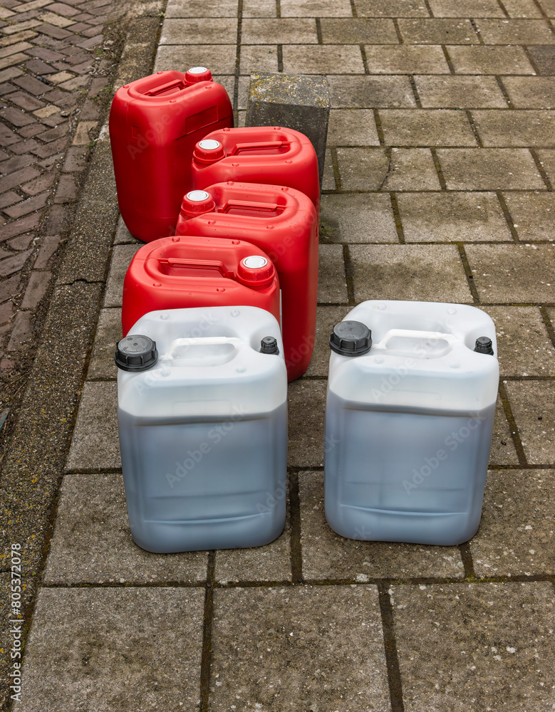 two transparent oil cans and four red oil cans