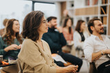 Fototapeta  - Smiling woman participating in a professional workshop with colleagues in a modern office setting, conveying engagement and teamwork.