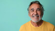 © Wonderful Studio - A man with a beard and gray hair is smiling and wearing a yellow shirt